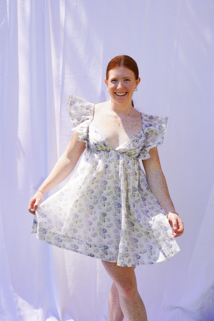 Women wearing blue floral organza dress with ruffle sleeves and bow back