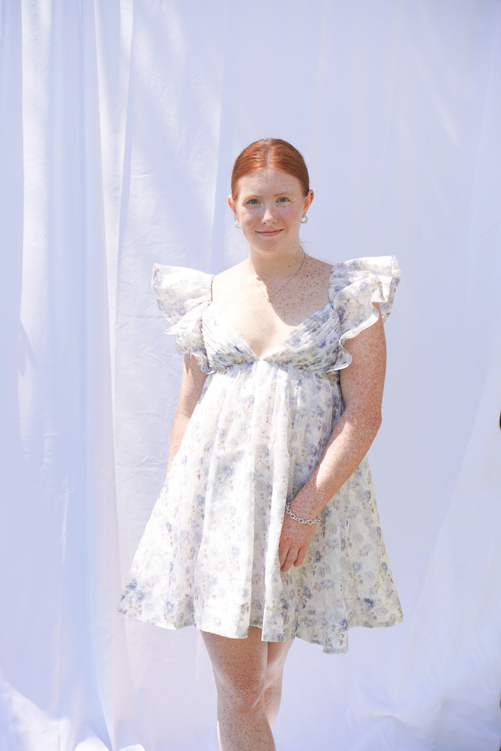 Women wearing blue floral organza dress with ruffle sleeves and bow back